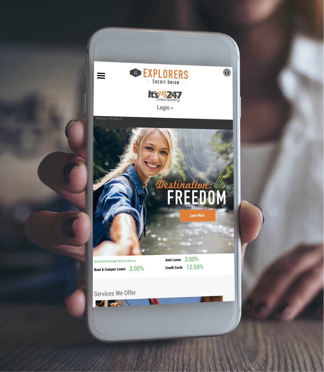 A mobile phone displaying the new website on the screen.